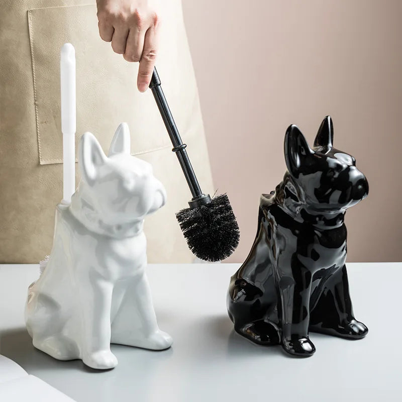 Hand holding a toilet brush next to black and white ceramic dog-shaped toilet brush holders on a flat surface.