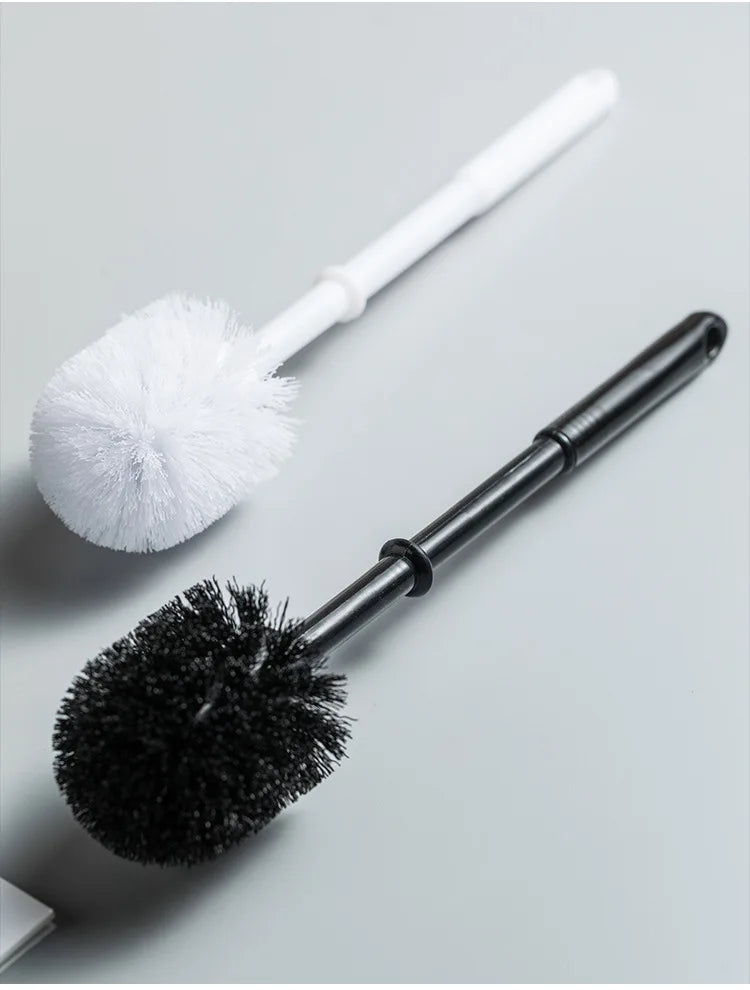 Two cleaning brushes, one white and fluffy, the other black with bristles, on a light gray background.